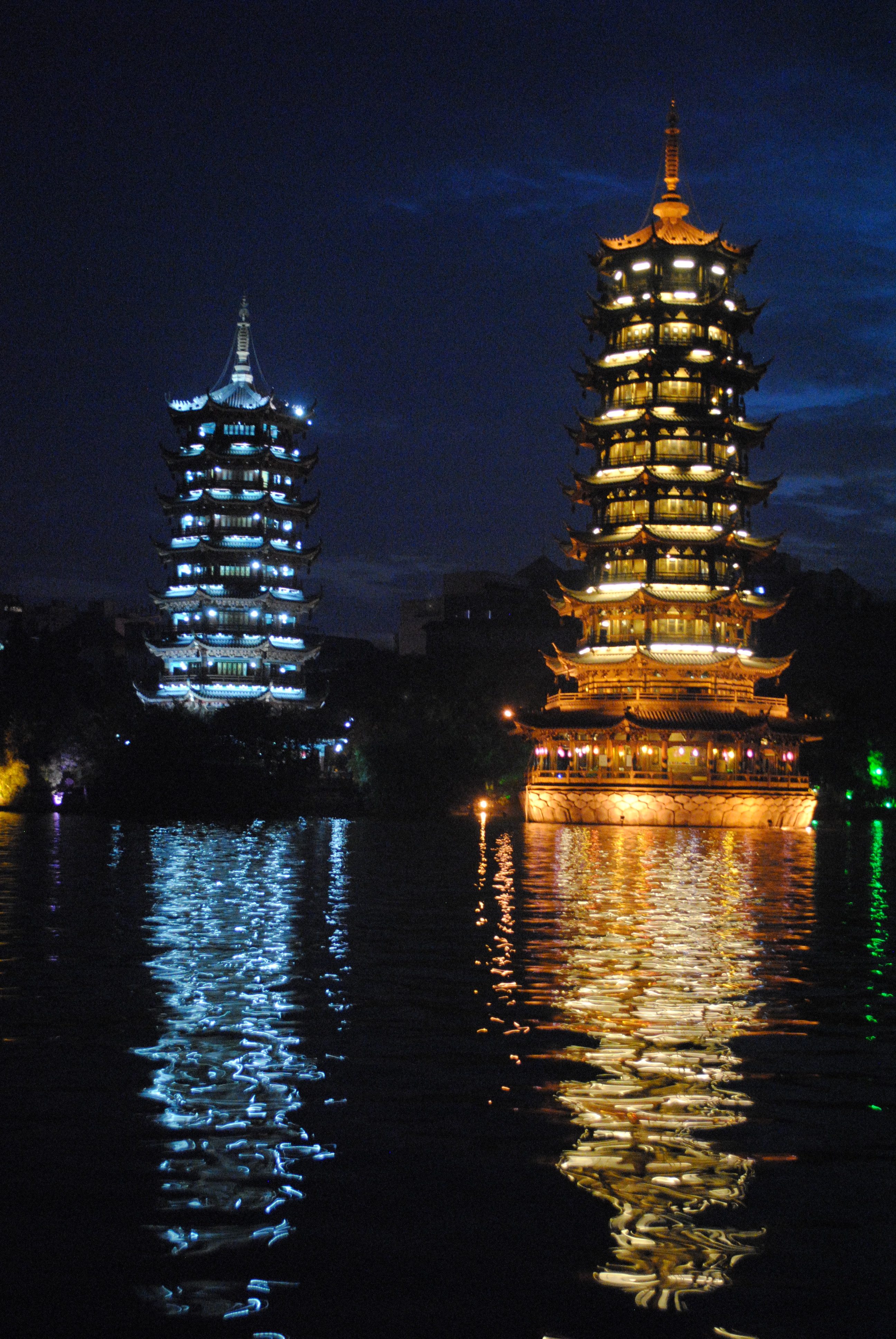 The Guilin towers in Guangxi province, China. It is nighttime and the towers are lit up.