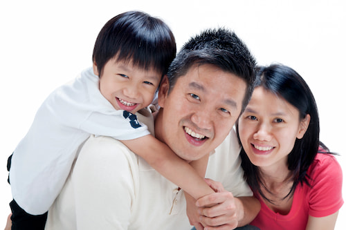 A family of 3 smiling for a photo together.