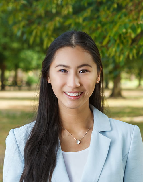 A head and shoulders photo of Fiona. She has long dark hair and is wearing a light blue blazer.