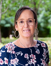 A head and shoulders photo of Kellie. She has dark hair tied back. She is wearing glasses and hoop earrings.